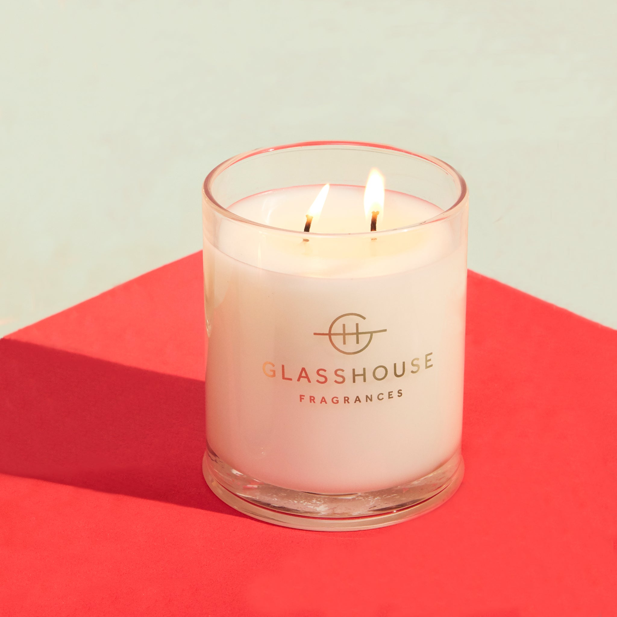 Glasshouse Fragrances Soy Candle burning on red tabletop
