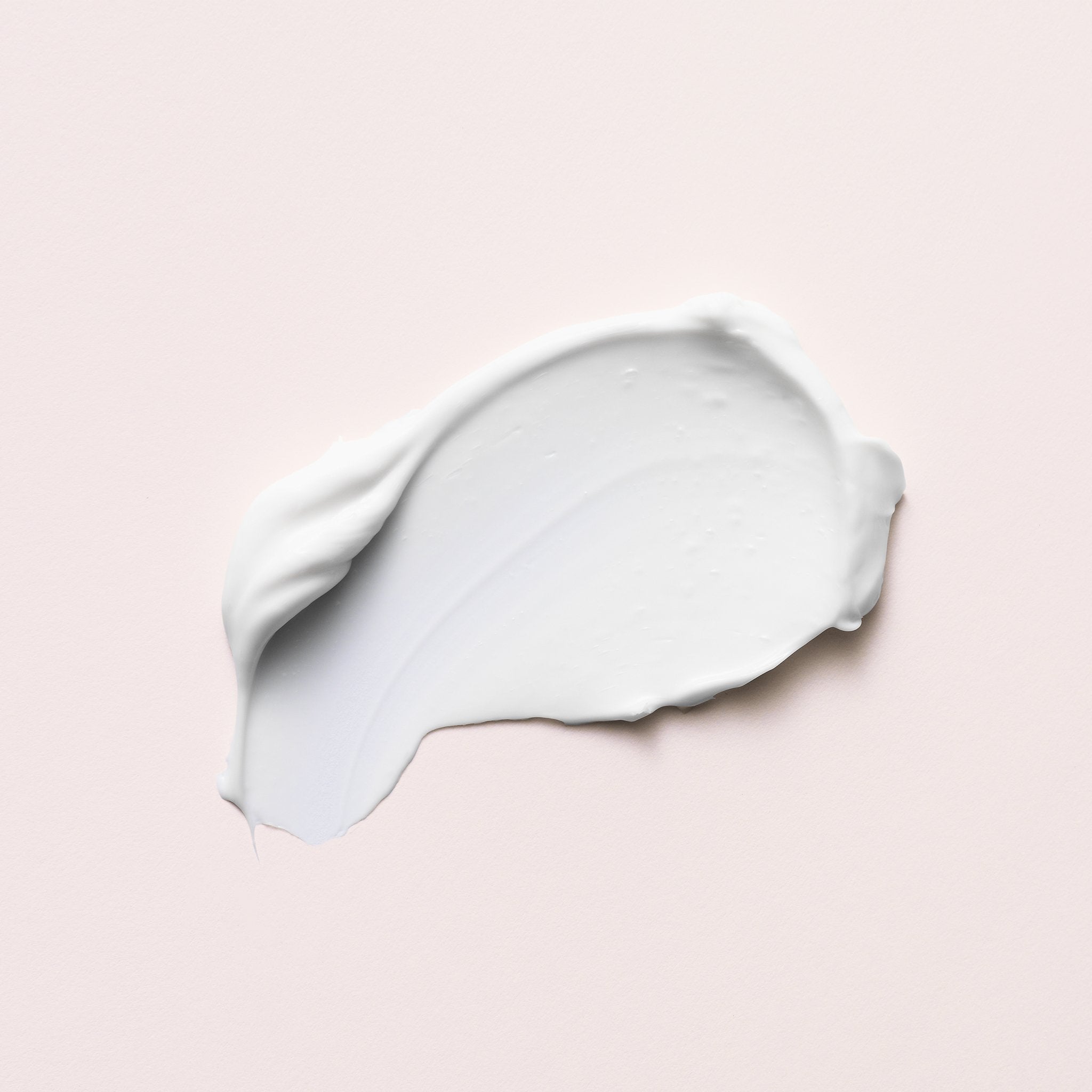 A smear of bright white cream on off-white background
