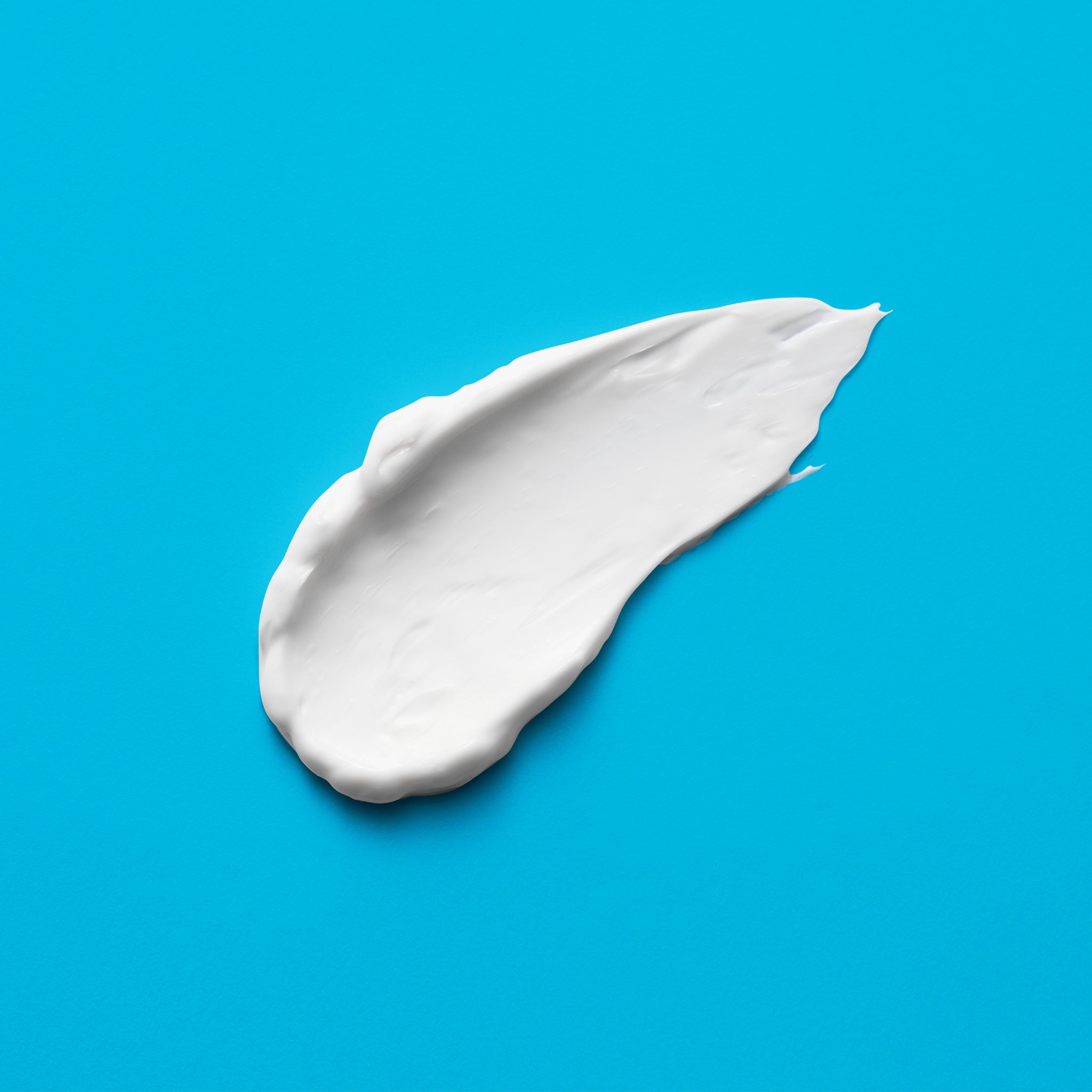 A smear of bright white cream on a light blue background