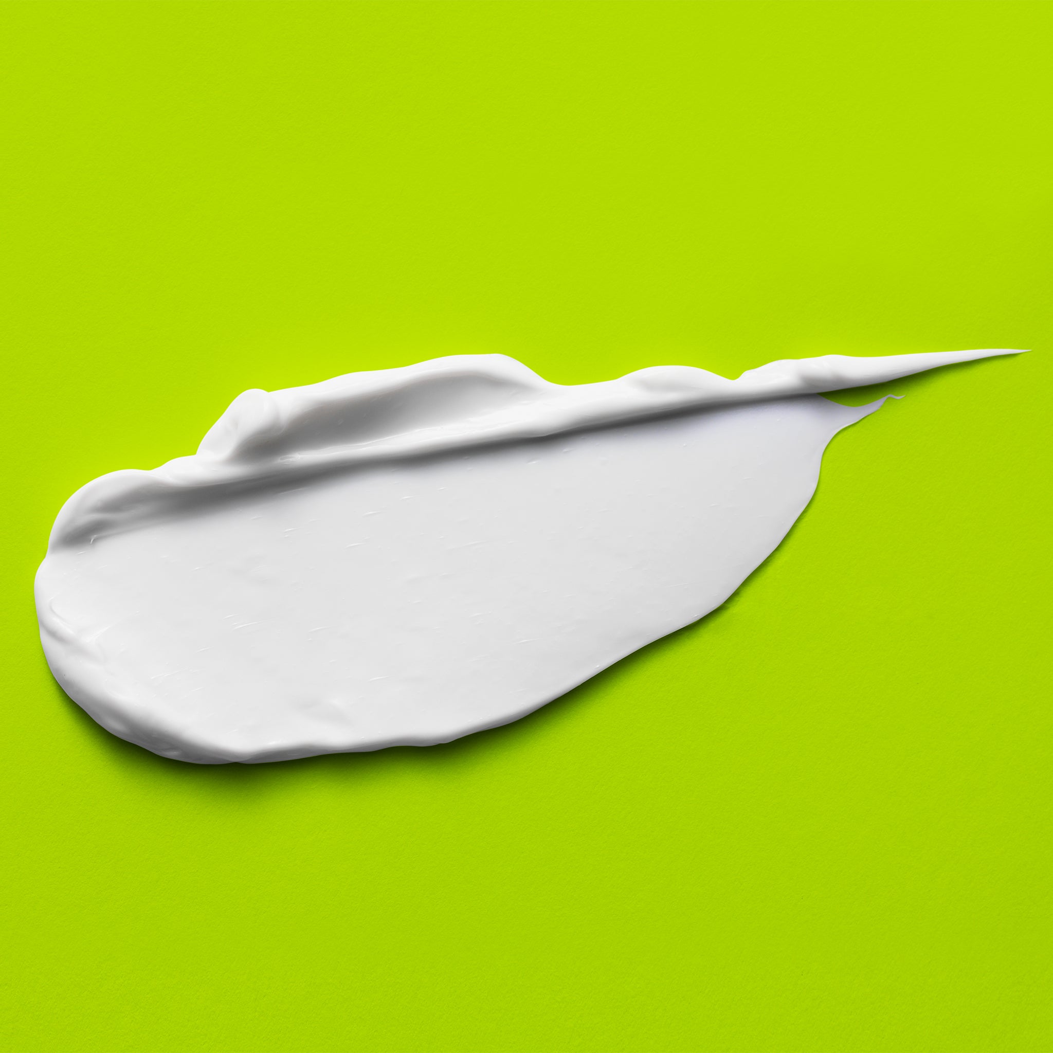 A smear of bright white cream on a bright lime-green background